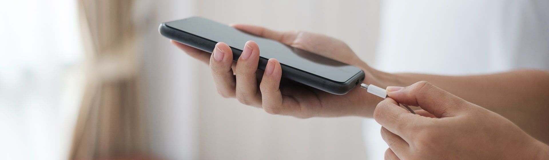 Mão conectado o carregador em um celular preto