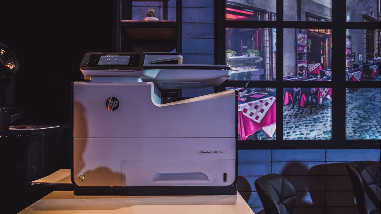 Impressora HP branca em cima de mesa de madeira