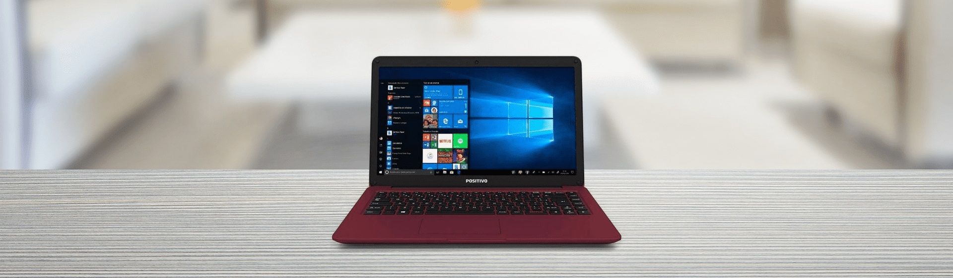 Notebook Positivo vermelho sobre mesa de madeira clara