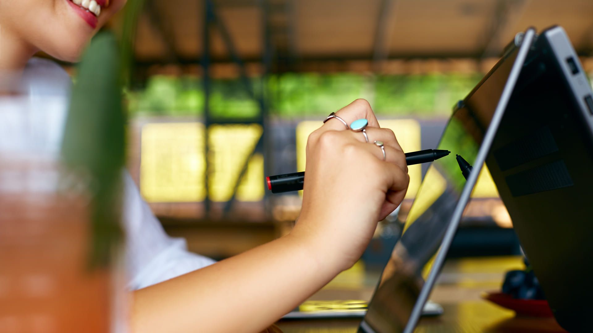 Mulher usando um notebook touchscreen desenhando algo na tela dele com caneta stylus
