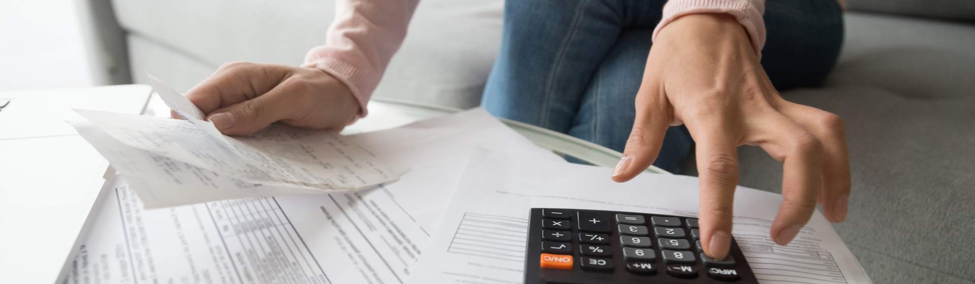 Pessoa digitando em calculadora e vendo recibos de compras
