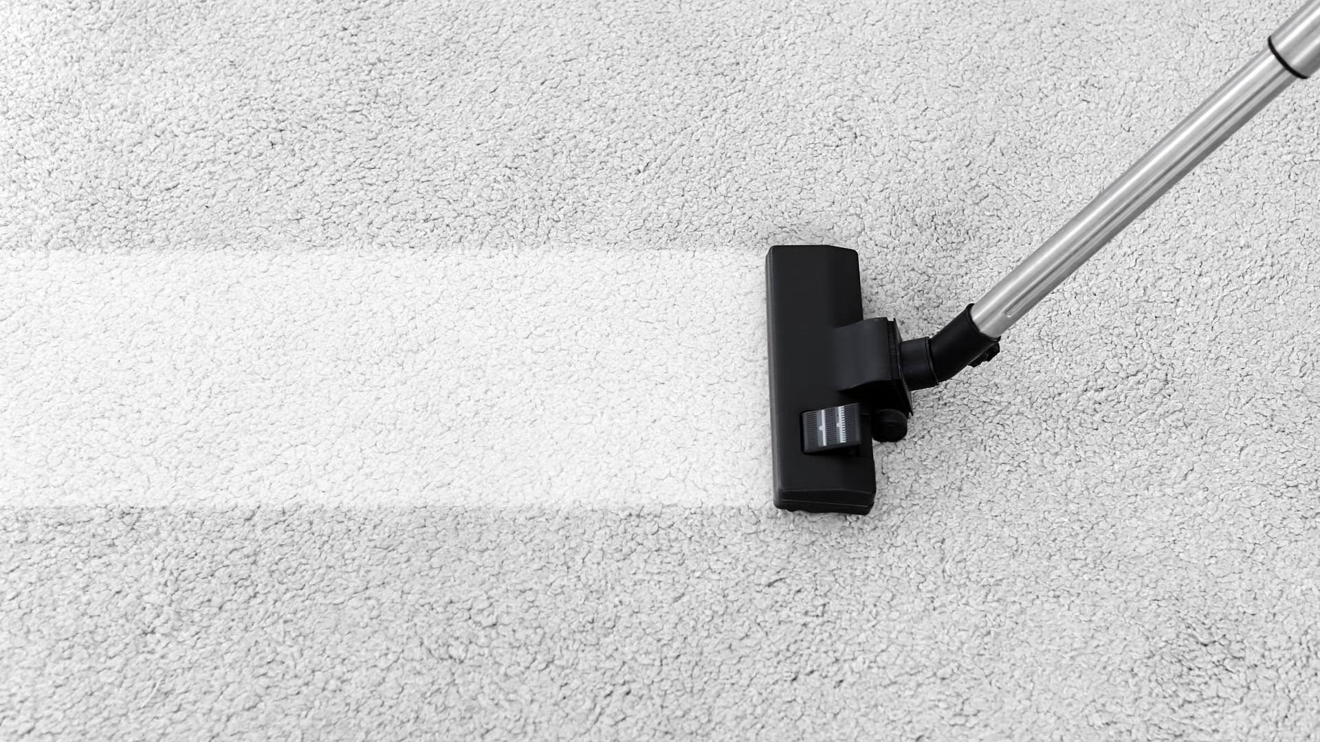 Aspirador de pó sendo usado para limpar um carpete cinza