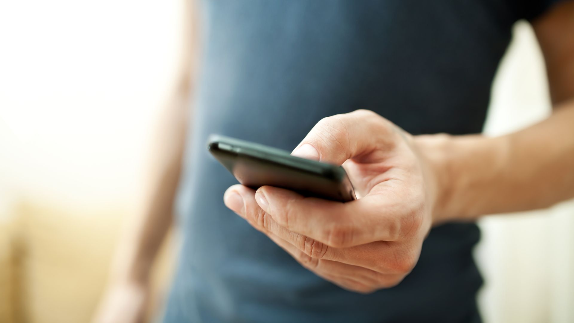 Celular na mão de homem com camisa azul