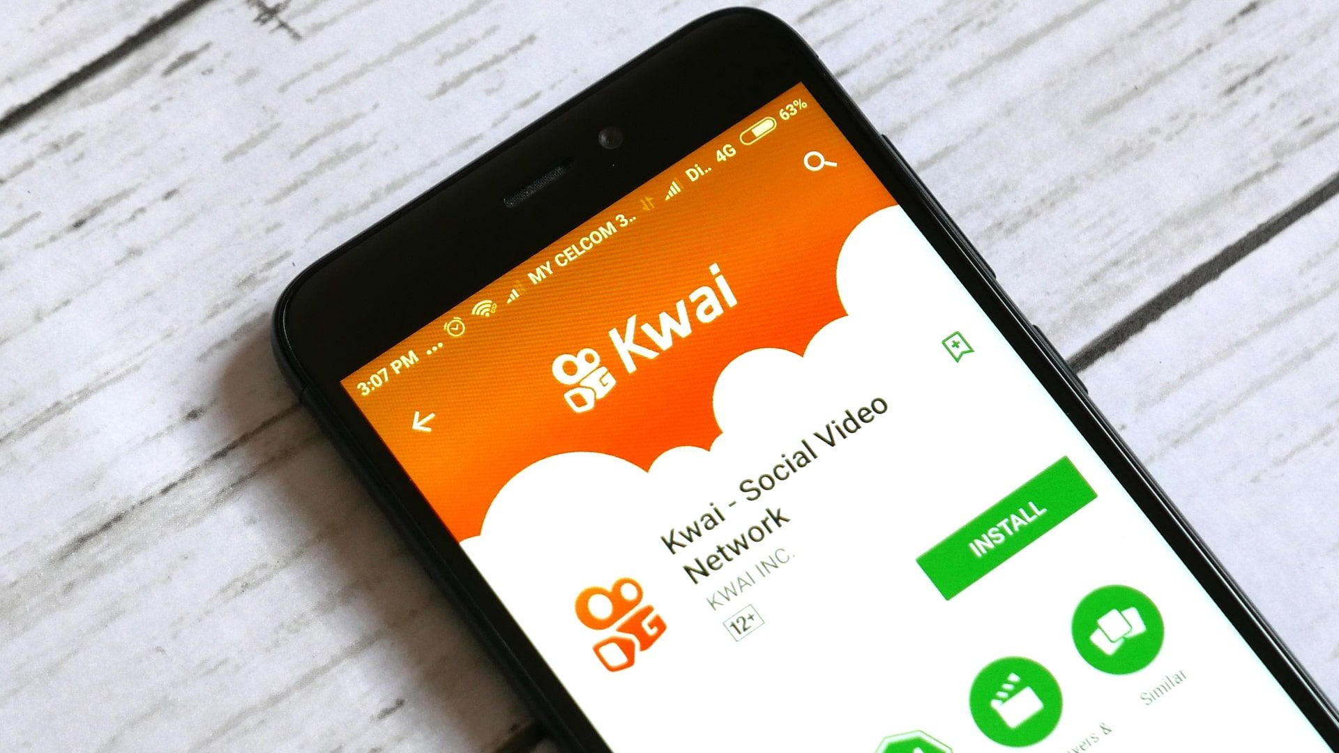 Kwai app on smartphone screen on orange background. Social media