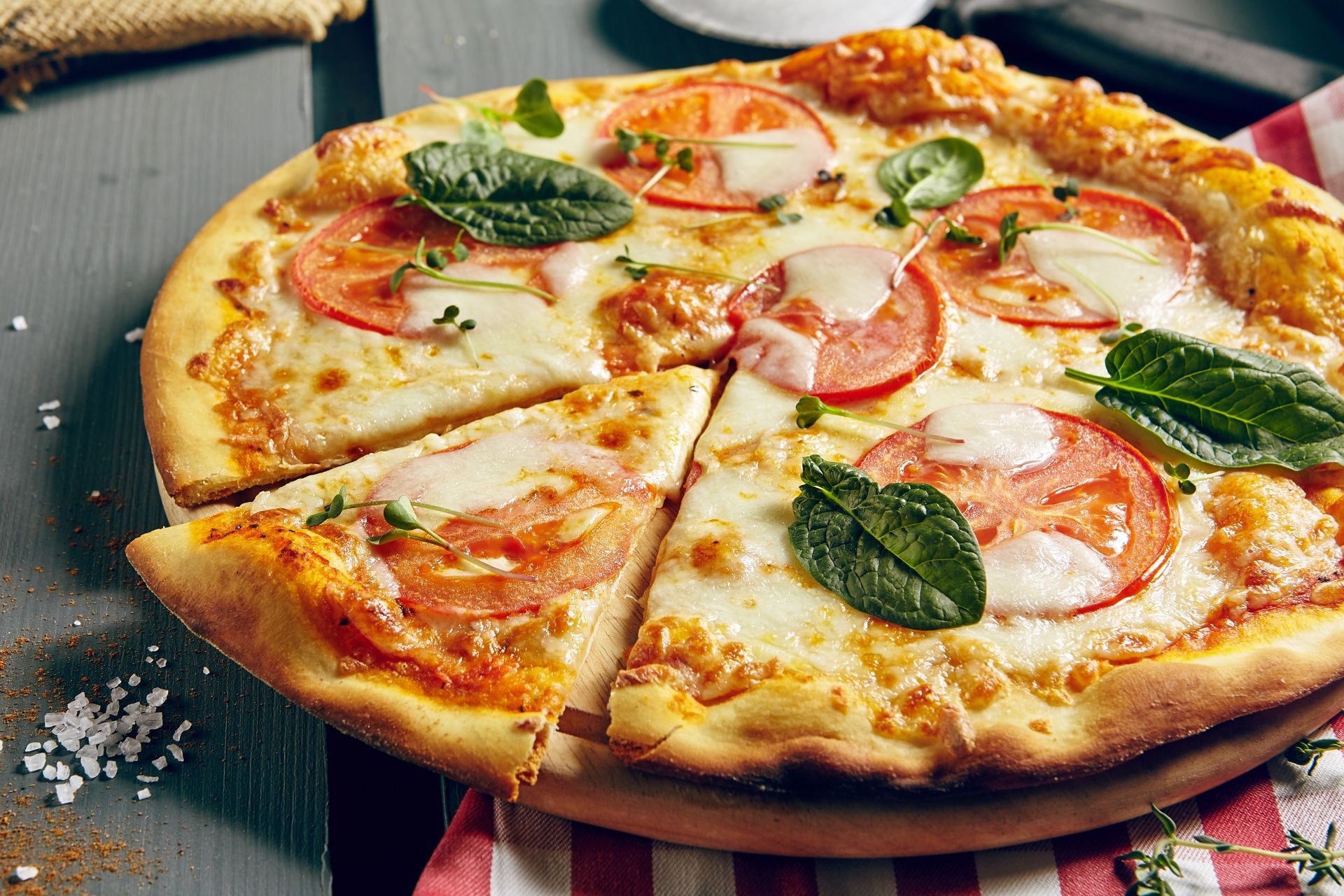 Pizza com mussarela, tomates e manjericão com fatia cortada