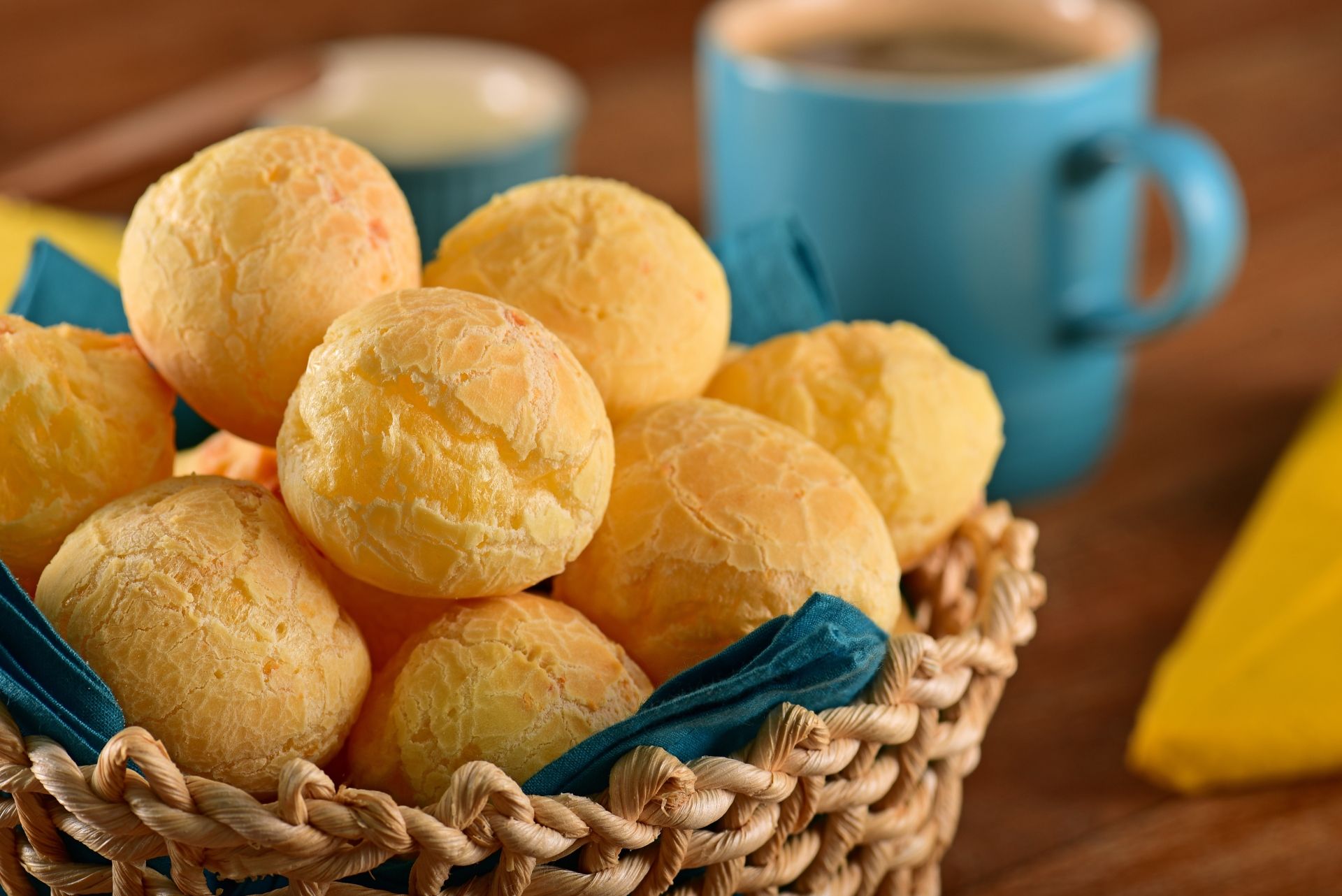 Cesto de vime com pães de queijo na frente de uma caneca de café