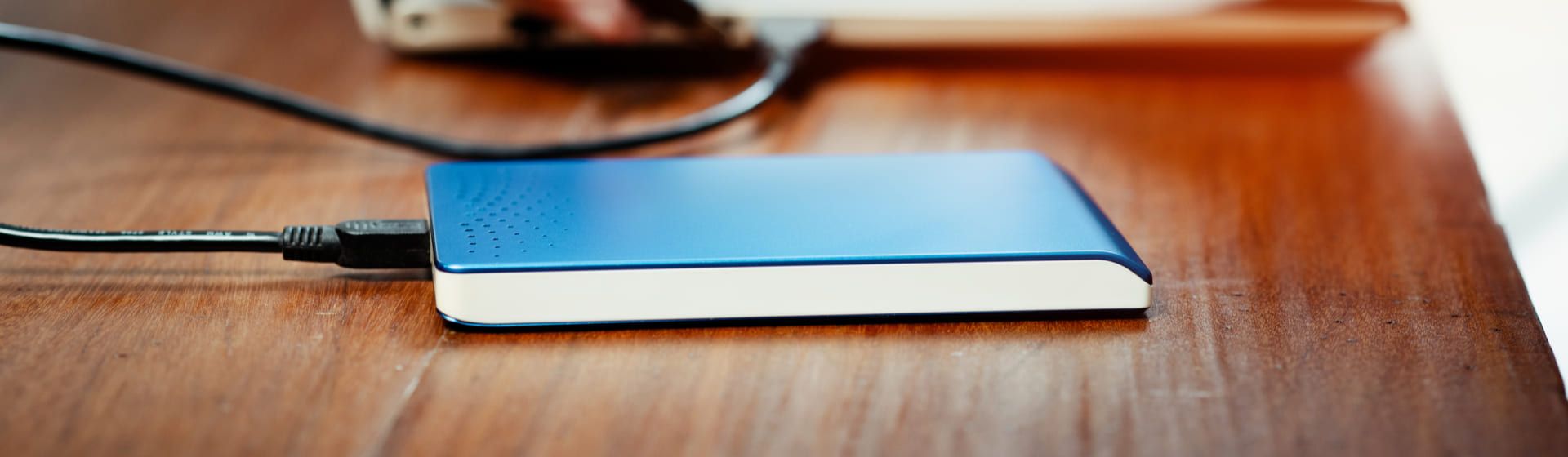 HD externo 1TB azul e branco em cima de mesa de madeira