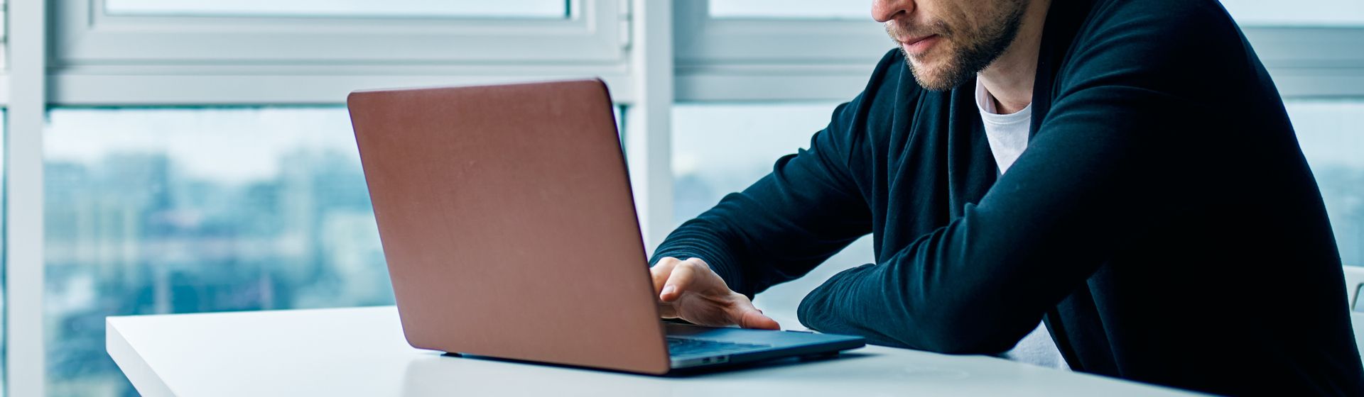 Homem mexe em notebook linux cinza em cima de mesa branca