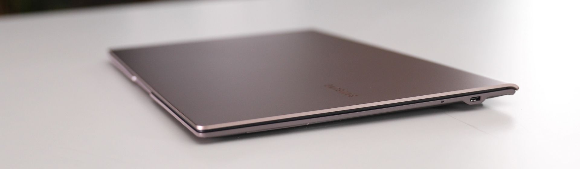 Notebook Samsung i5 cinza claro fechado em cima de uma mesa branca