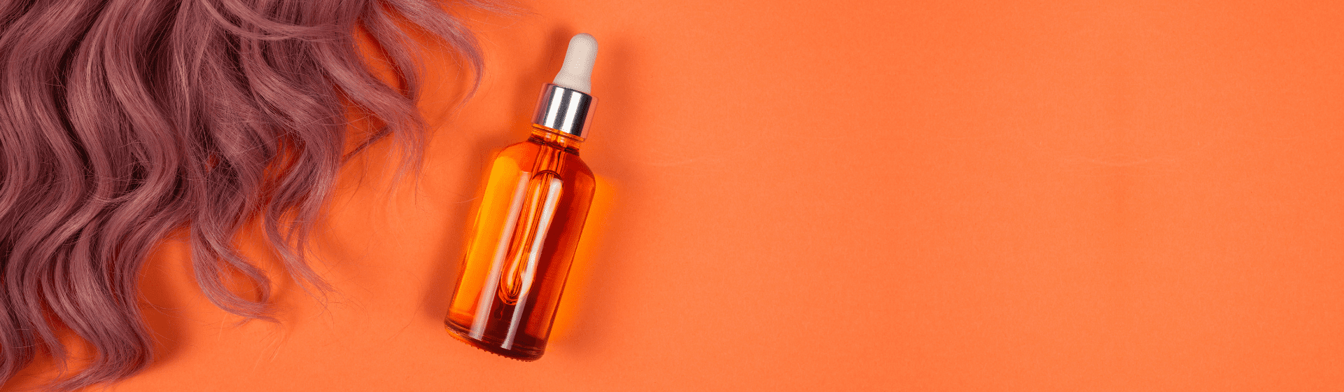 Óleo para cabelo em fundo laranja com cabelo colorido ao lado