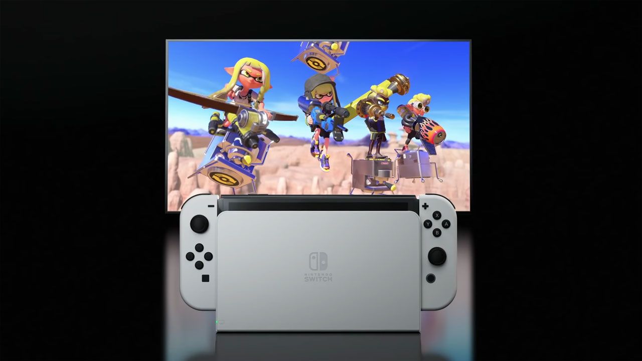 Nintendo Switch OLED na estrutura que o conecta à TV em primeiro plano, com televisão rodando os jogos em segundo plano.