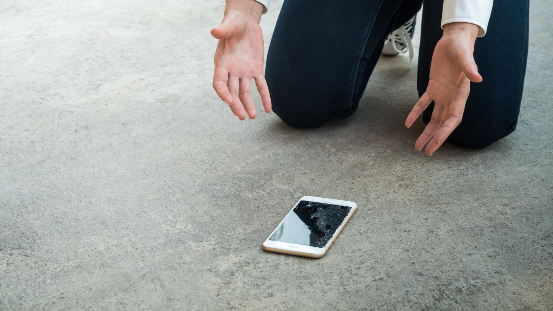 Foto mostra celular caído no chão com a tela trincada