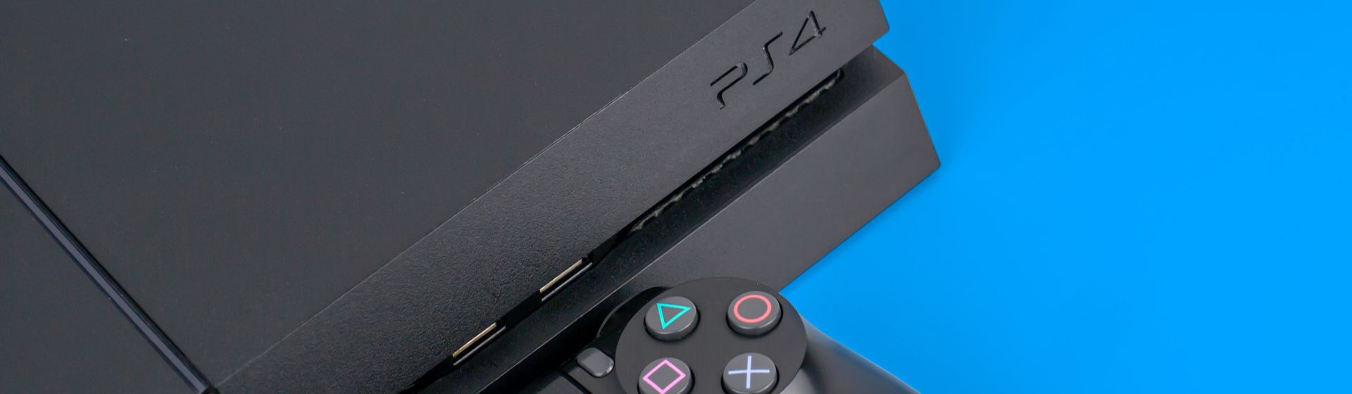 PS4 e controle DualShock 4 pretos sobre fundo azul