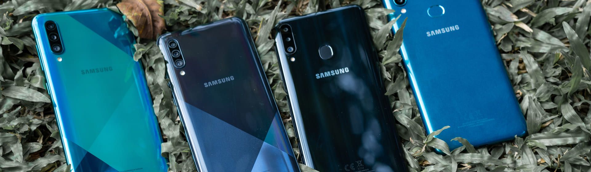 Quatro celulares Samsung lado a lado com traseira para cima sobre um gramado