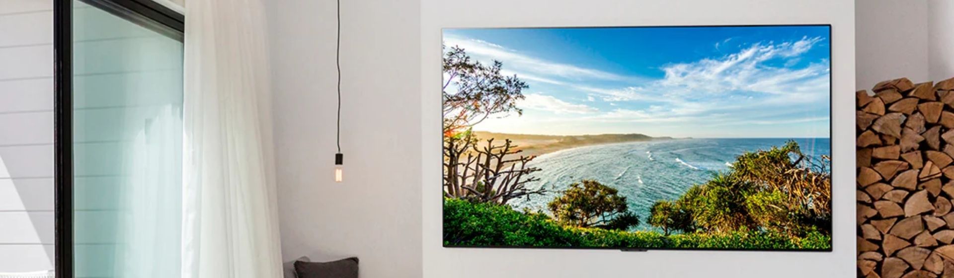 Smart TV LG G1 em uma parede branca exibindo imagem de uma praia
