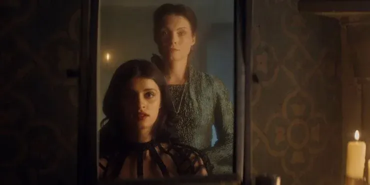 Yennefer de Vengerberg se olha no espelho depois de sua transformação e correção das suas deficiências. Atrás dela, Tissaia de Vries observa com olhar de aprovação