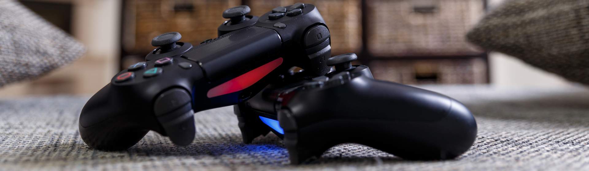 Dois controles de PlayStation 4 pretos sobre um tapete cinza