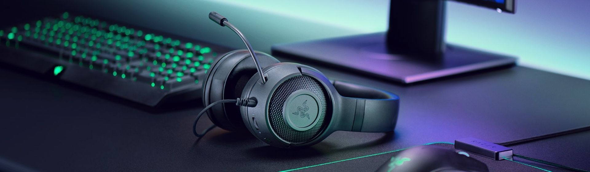 Headset Razer preto em cima de mesa ao lado de teclado e mouse