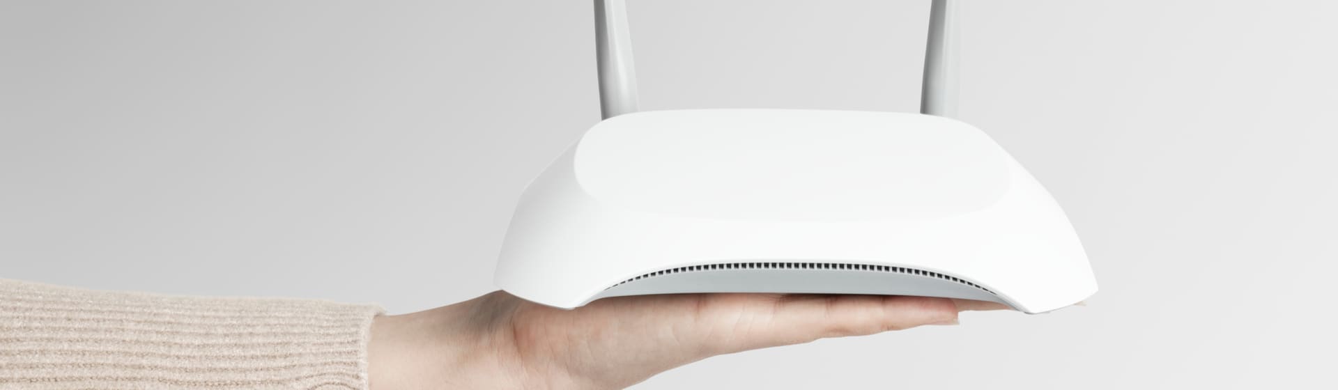 Mão segurando roteador Intelbras branco