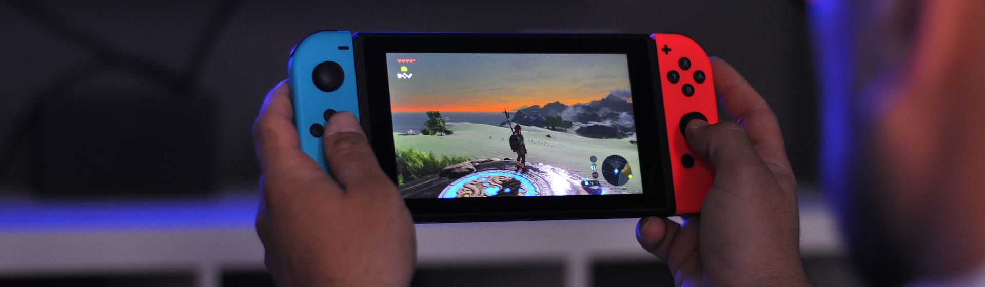 Duas mãos segurando um videogame portátil Nintendo Switch