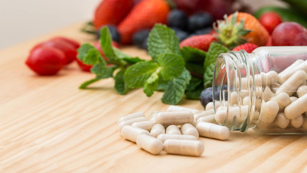 Vitaminas em cima de mesa de madeira ao lado de morangos