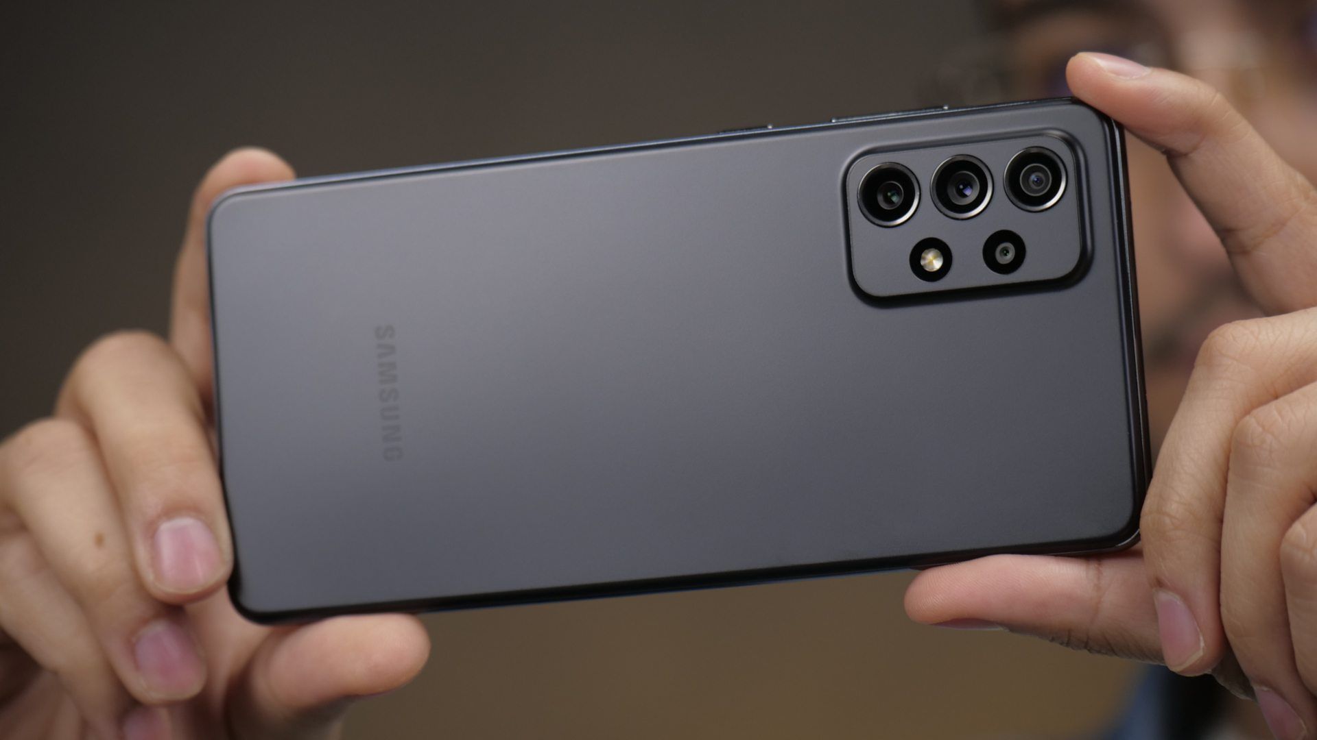 Homem segurando o celular Galaxy A72 preto na horizontal para tirar fotos