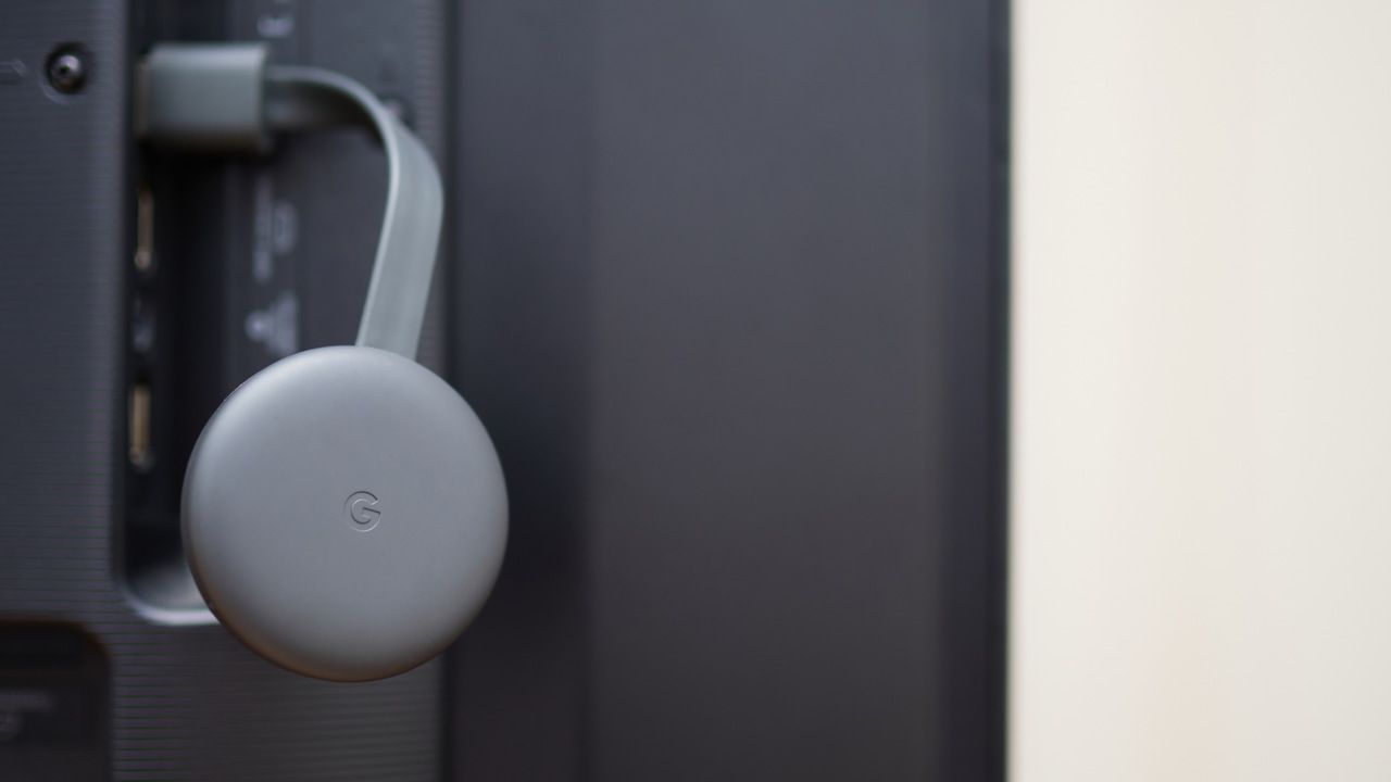Chromecast cinza instalado no HDMI de uma TV