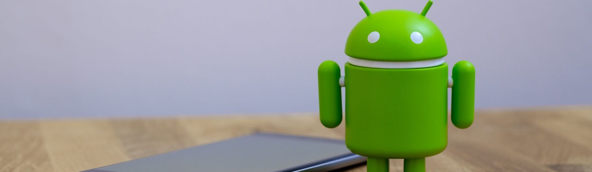 Robô Android ao lado de celular em cima de uma mesa