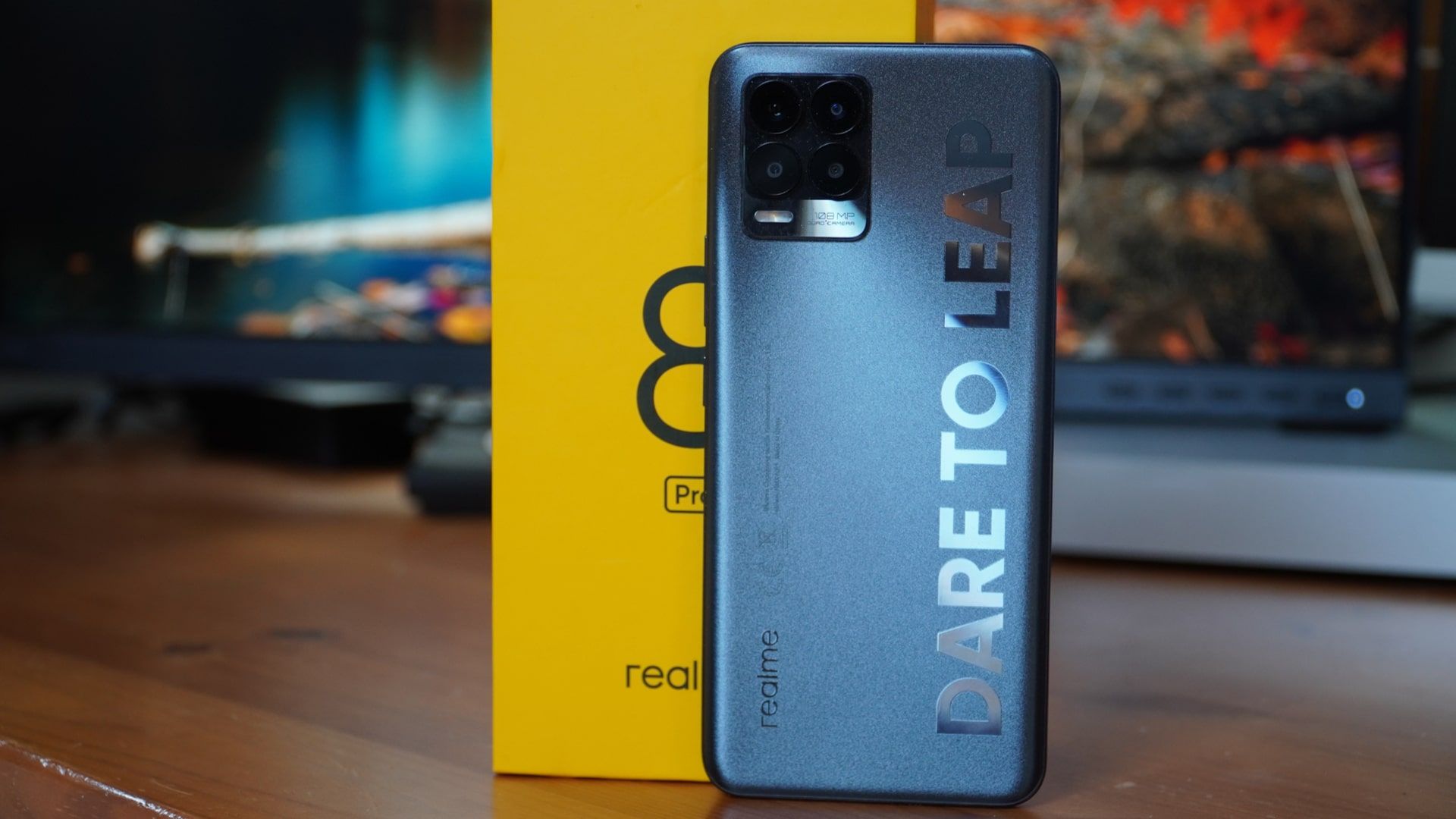 Celular Realme 8 Pro na cor cinza em pé, apoiado na caixa do smartphone