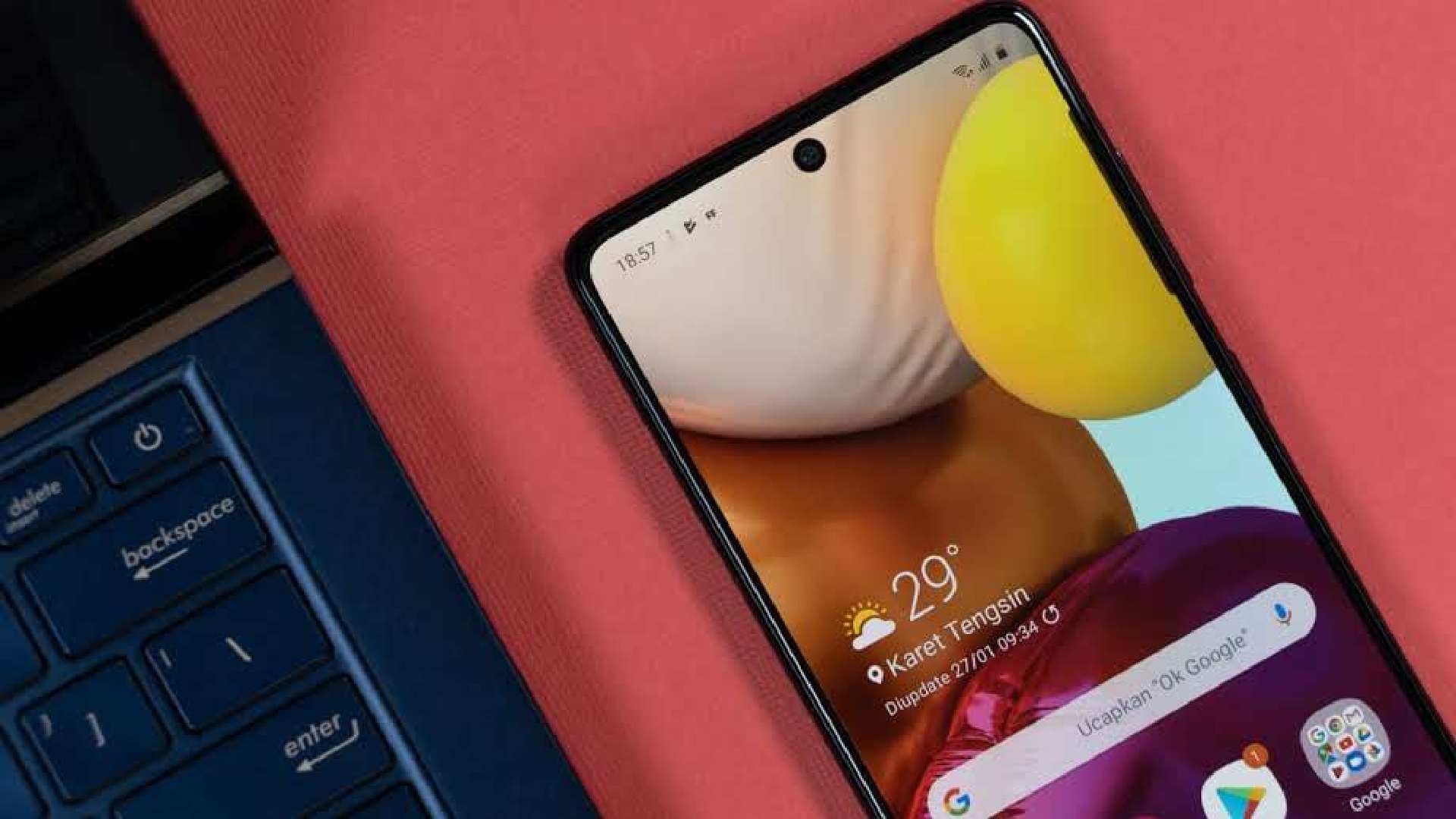 Galaxy A71 apoiado em mesa rosa aolado de notebook