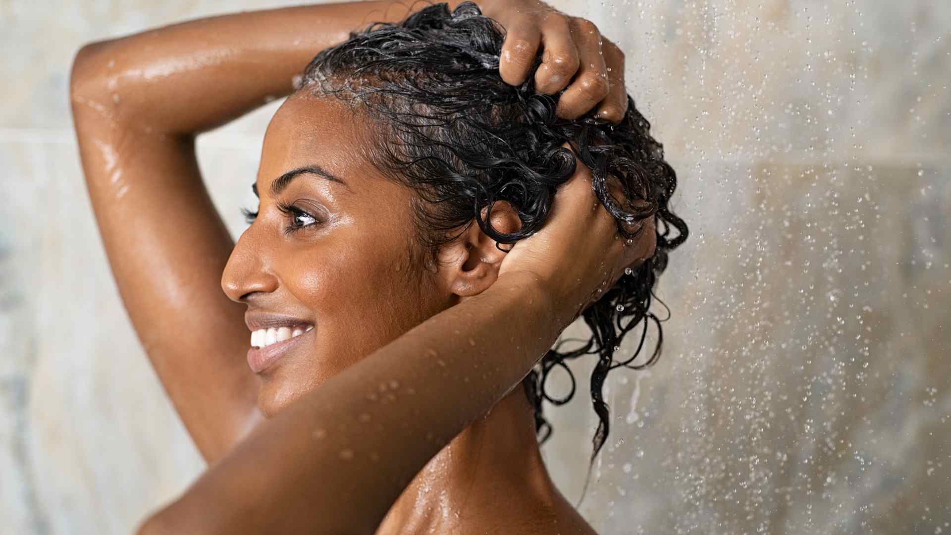 Mulher negra lavando os cabelos com shampoo