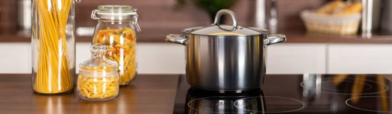 Panela de inox sobre fogão de indução instalado em bancada de madeira