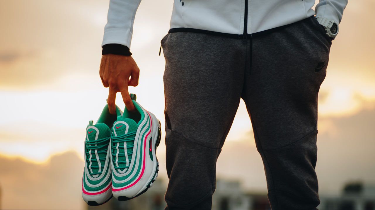 Homem segurando um tênis Nike Air Max em tons de verde, rosa e branco