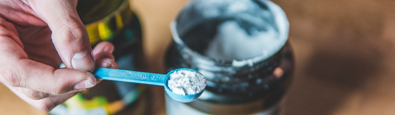 Indivíduo segurando uma porção de glutamina sobre a embalagem do produto