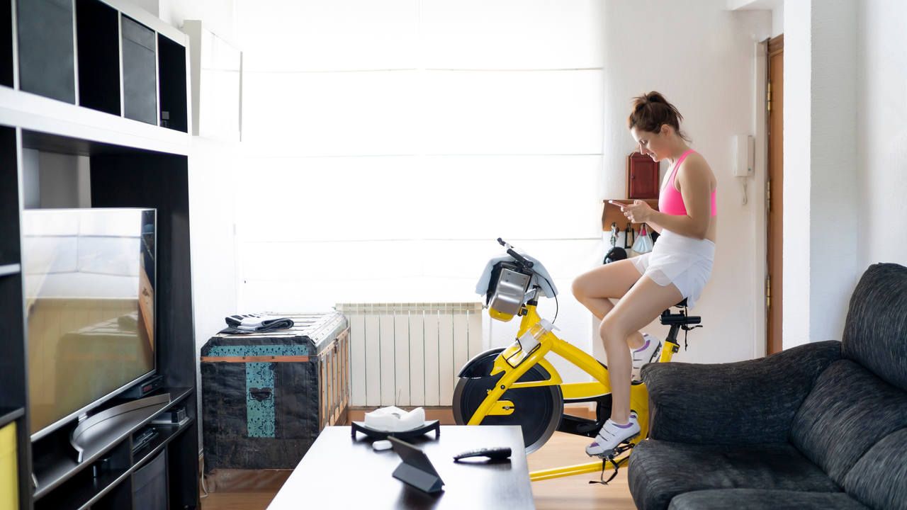 Mulher usa bicicleta ergométrica em casa