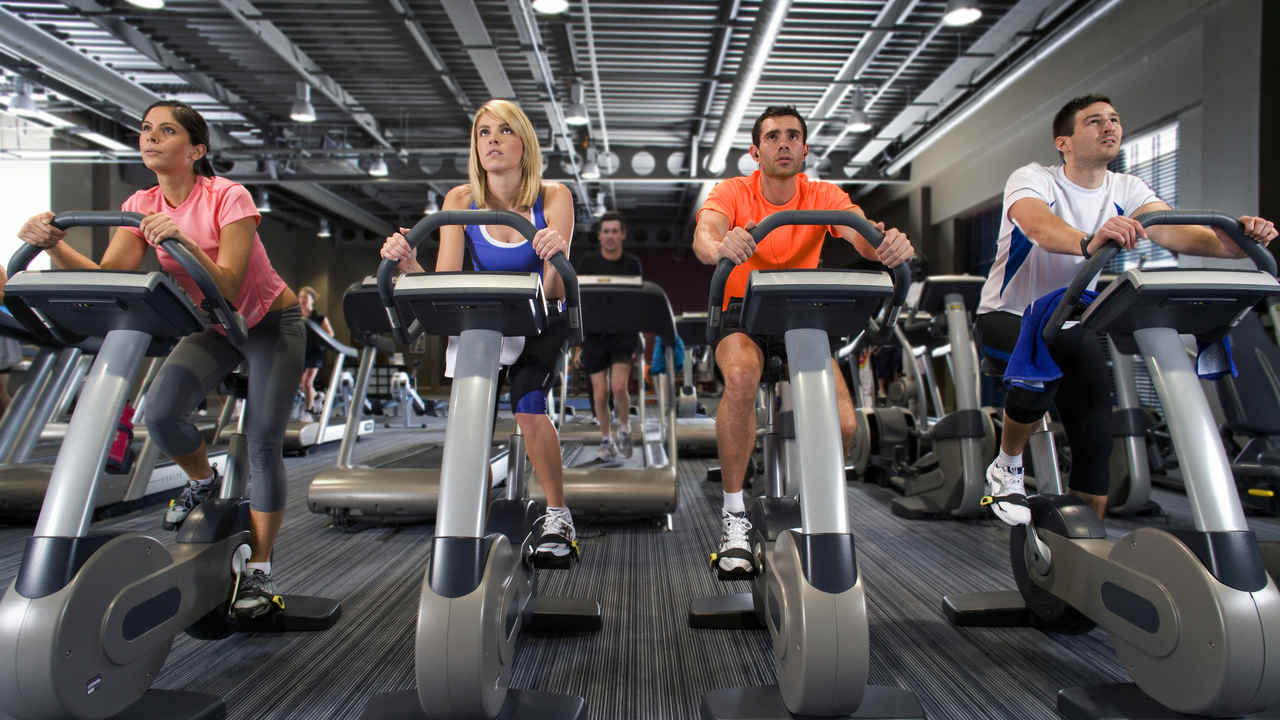 Bicicletas ergométricas sendo usadas por pessoas em uma academia