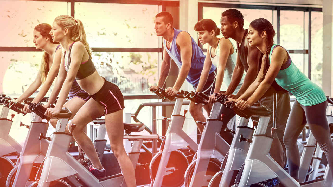 Bicicletas de spinning sendo usadas por alunos em uma aula coletiva