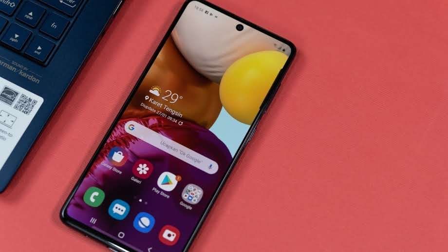 Galaxy A71 apoiado em mesa rosa ao lado de notebook