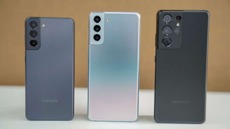 Três Galaxy S21 apoiados em mesa branca com fundo marrom
