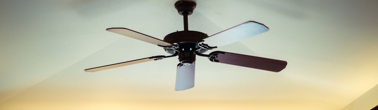 Ventilador de teto com pás de madeira e corpo preto instalado em teto branco
