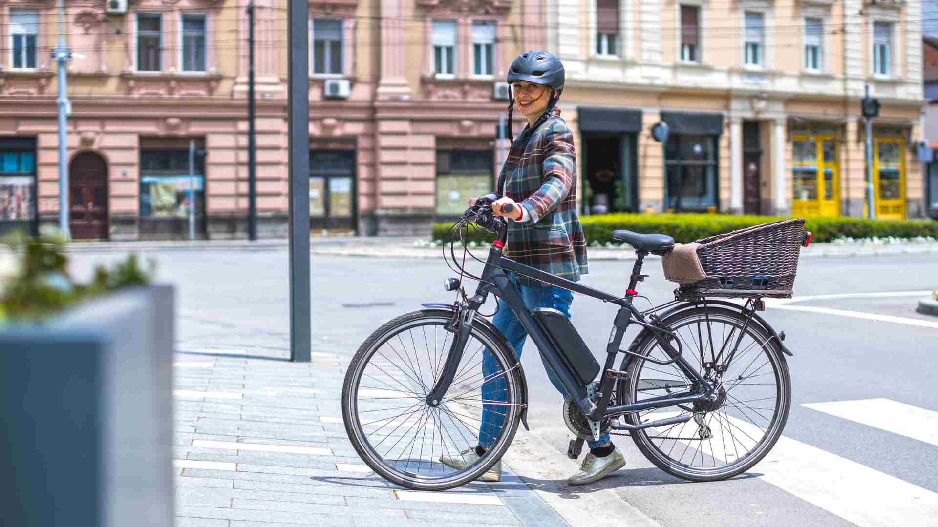 Mulher empurrando a bicicleta elétrica na faixa de pedestres
