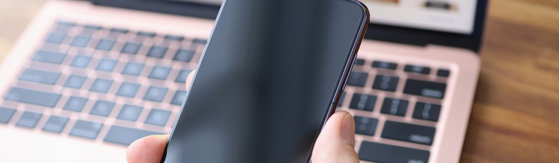 Celular Samsung Galaxy S21 nas mãos de homem com computador ao fundo