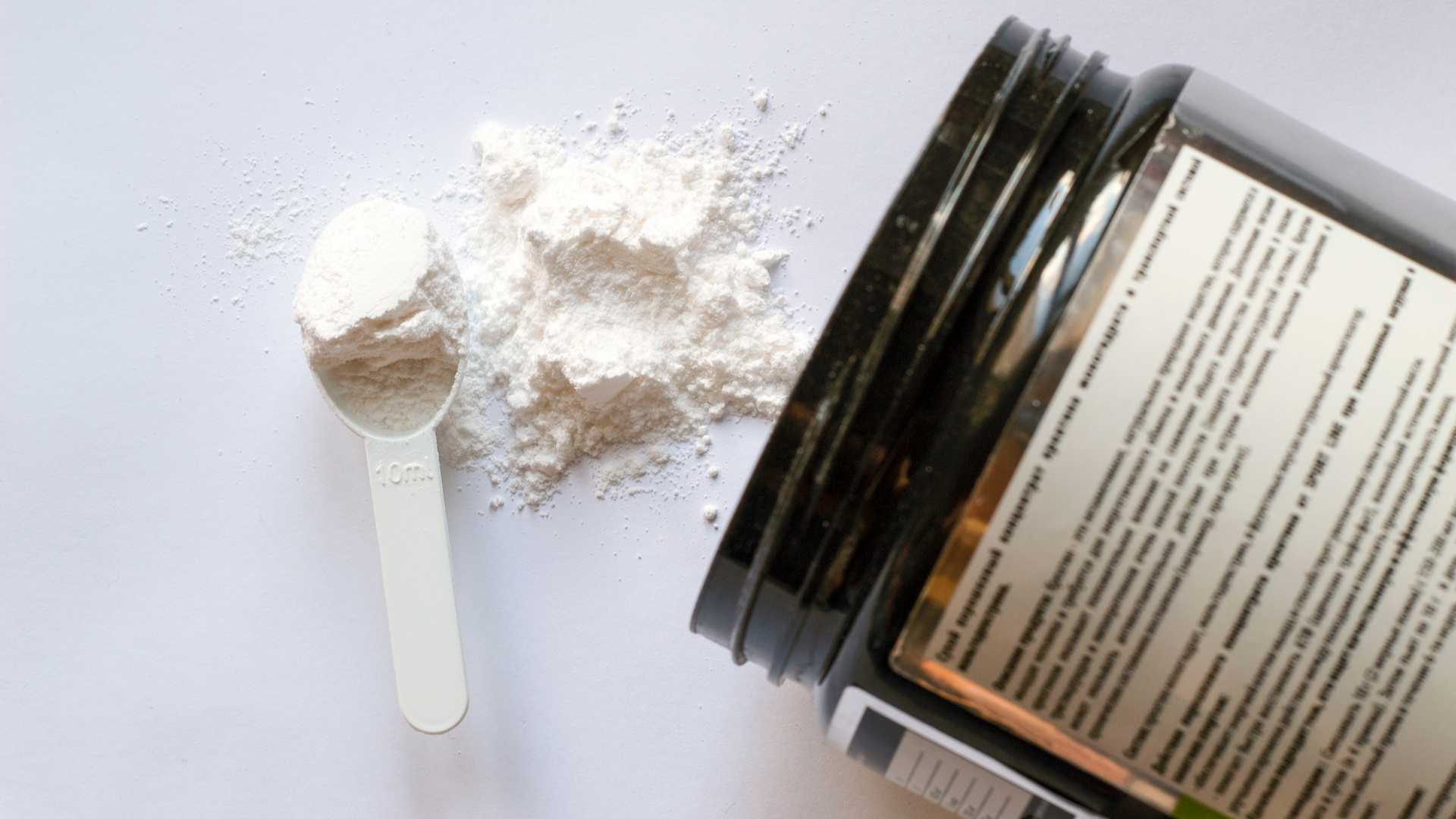 Pote de creatina ao lado de medidor cheio de creatina