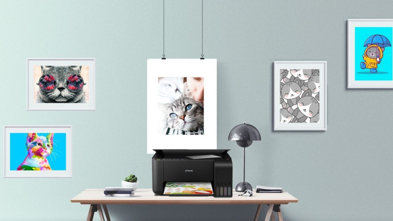 Impressora Epson Ecotank preta em cima de mesa de madeira com parede azul clara ao fundo