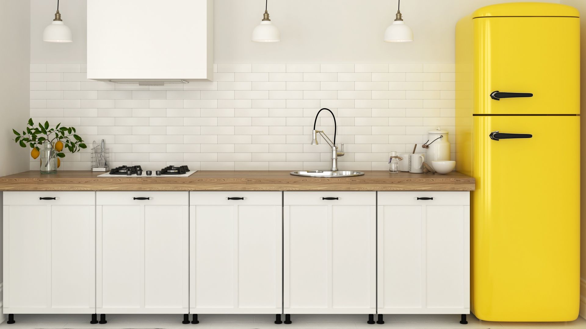 Geladeira duplex amarela à extrema direita da imagem ao lado de uma bancada de cozinha com armários brancos, pia e cooktop 