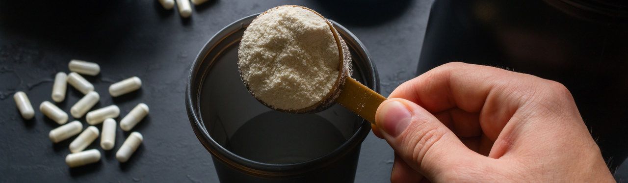 Mão masculin enchendo coqueteleira com suplemento branco
