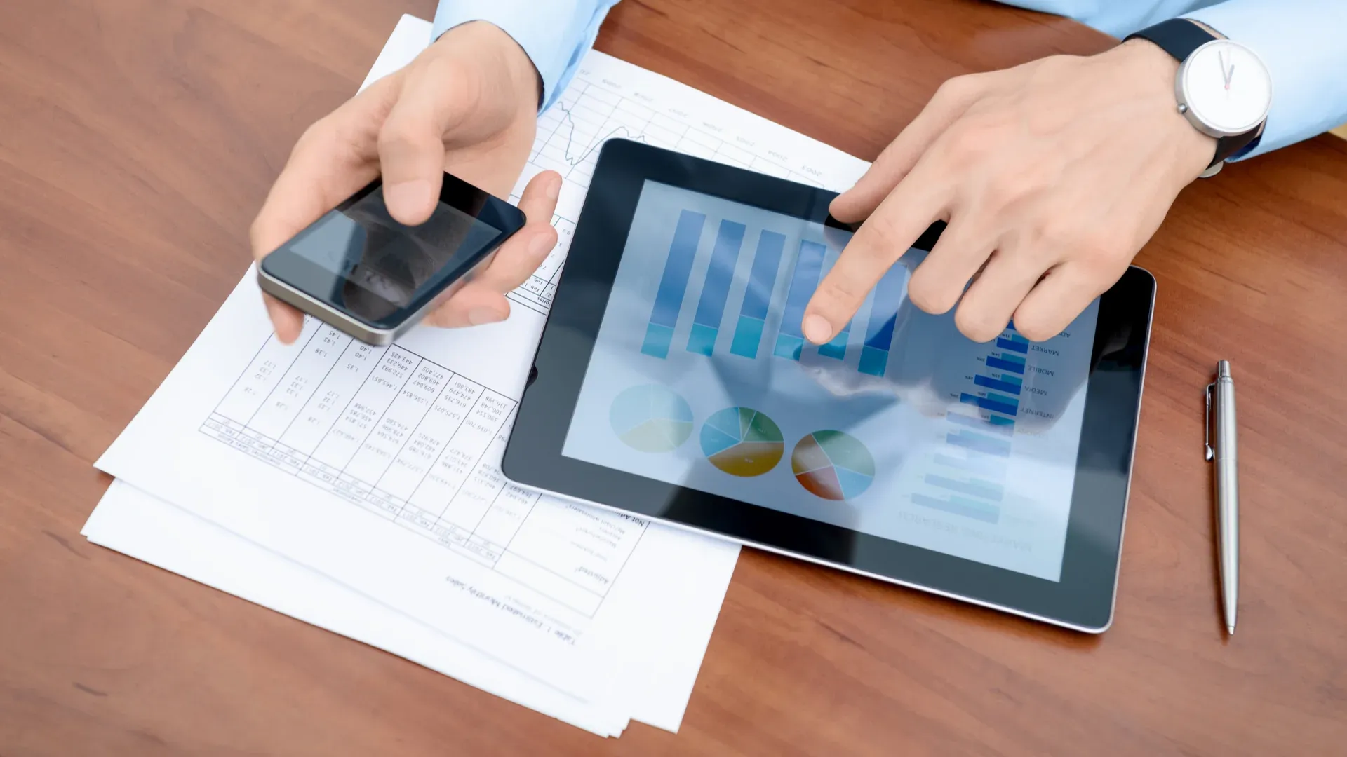 Pessoa com uma mão mexendo em um tablet e outra, em um celular