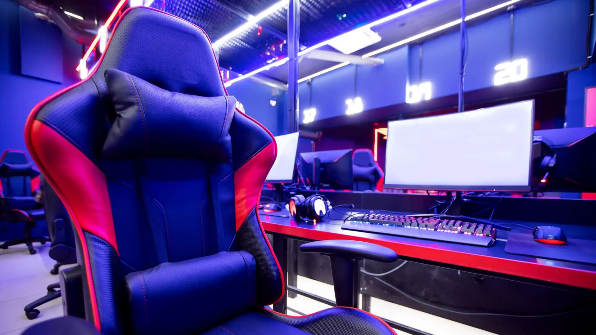 Cadeira gamer vermelha e preta com mesa com setup gamer à frente