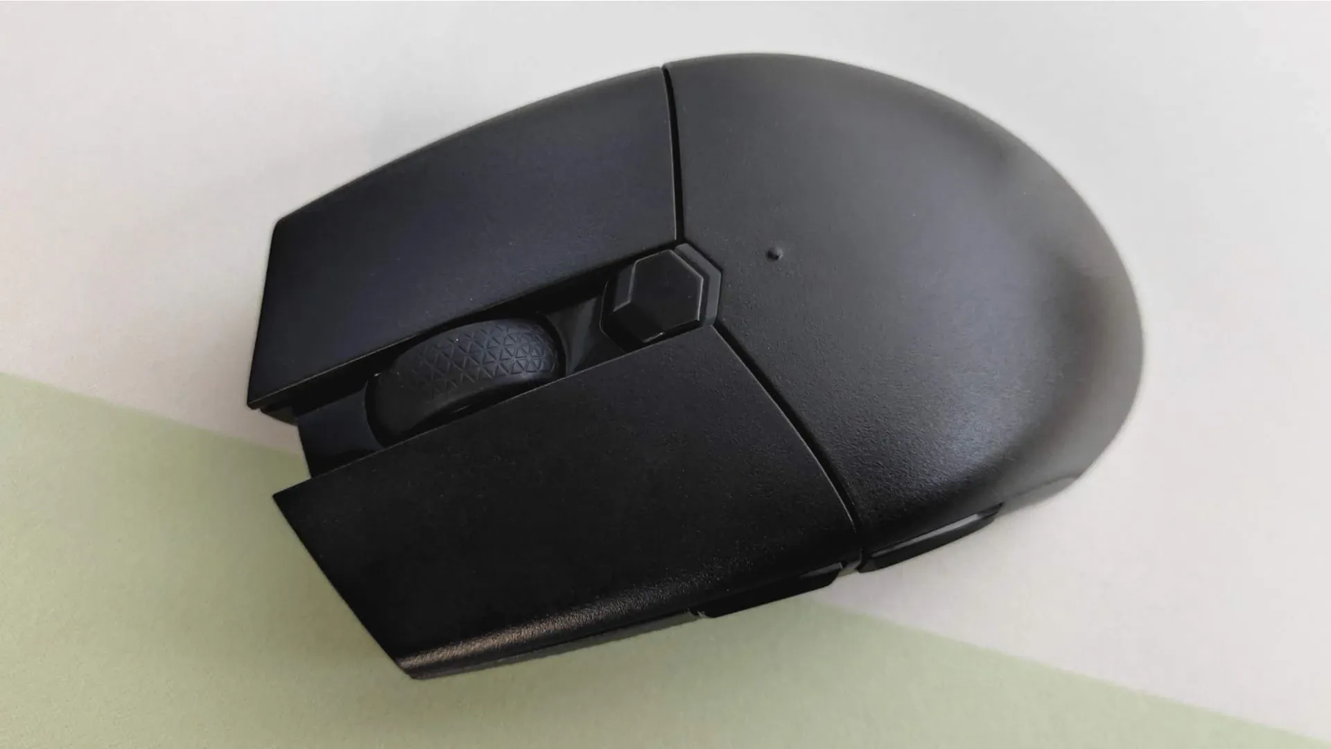 Mouse gamer preto com formato "claw" sobre mesa branca
