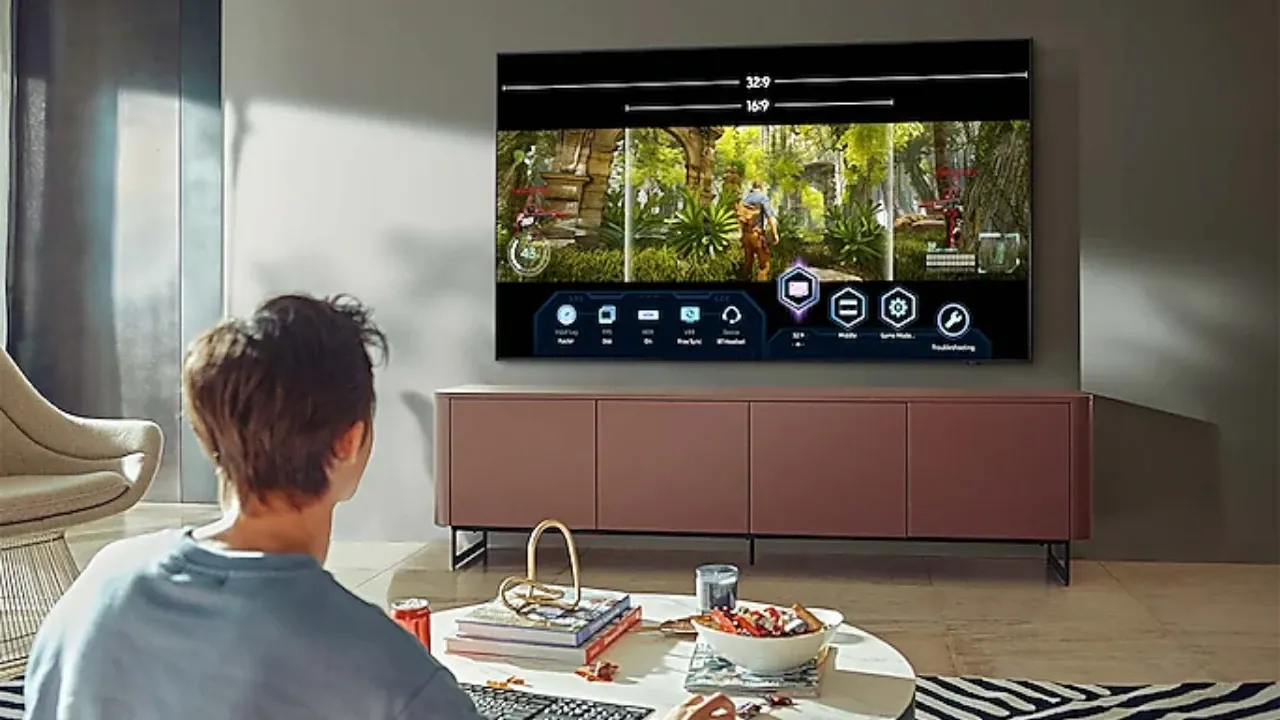 Homem branco sentado em frente à TV Samsung QN85A acessando menu de jogo na tela